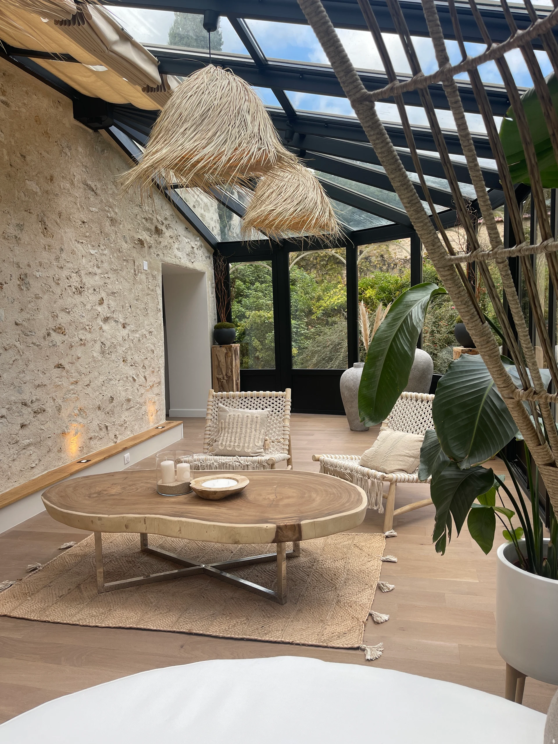La véranda avec son salon en rotin et ses grandes baies vitrées